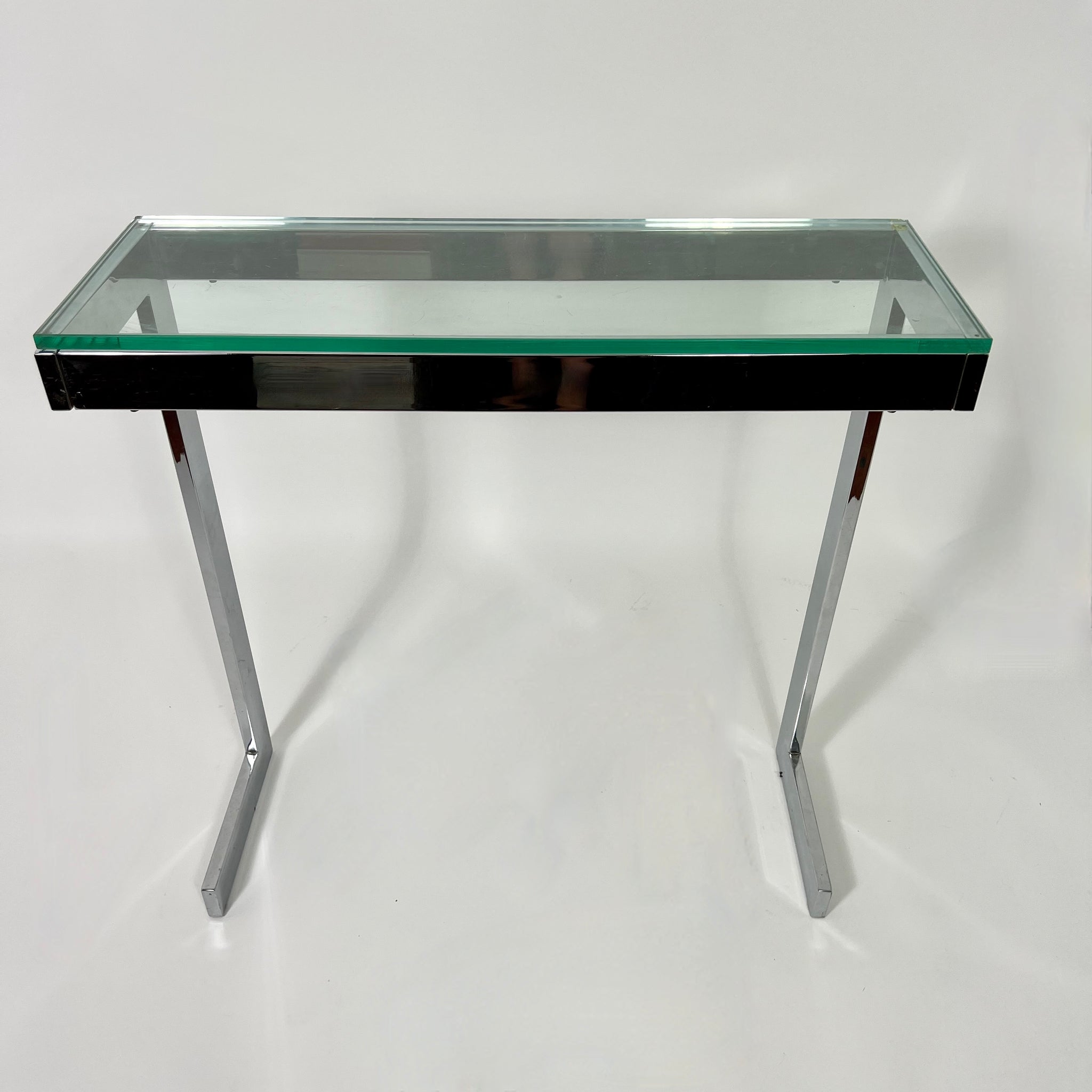 Pair of 1970's modernist chrome console tables with glass tops .