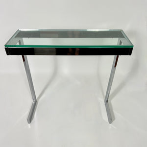 Pair of 1970's modernist chrome console tables with glass tops .