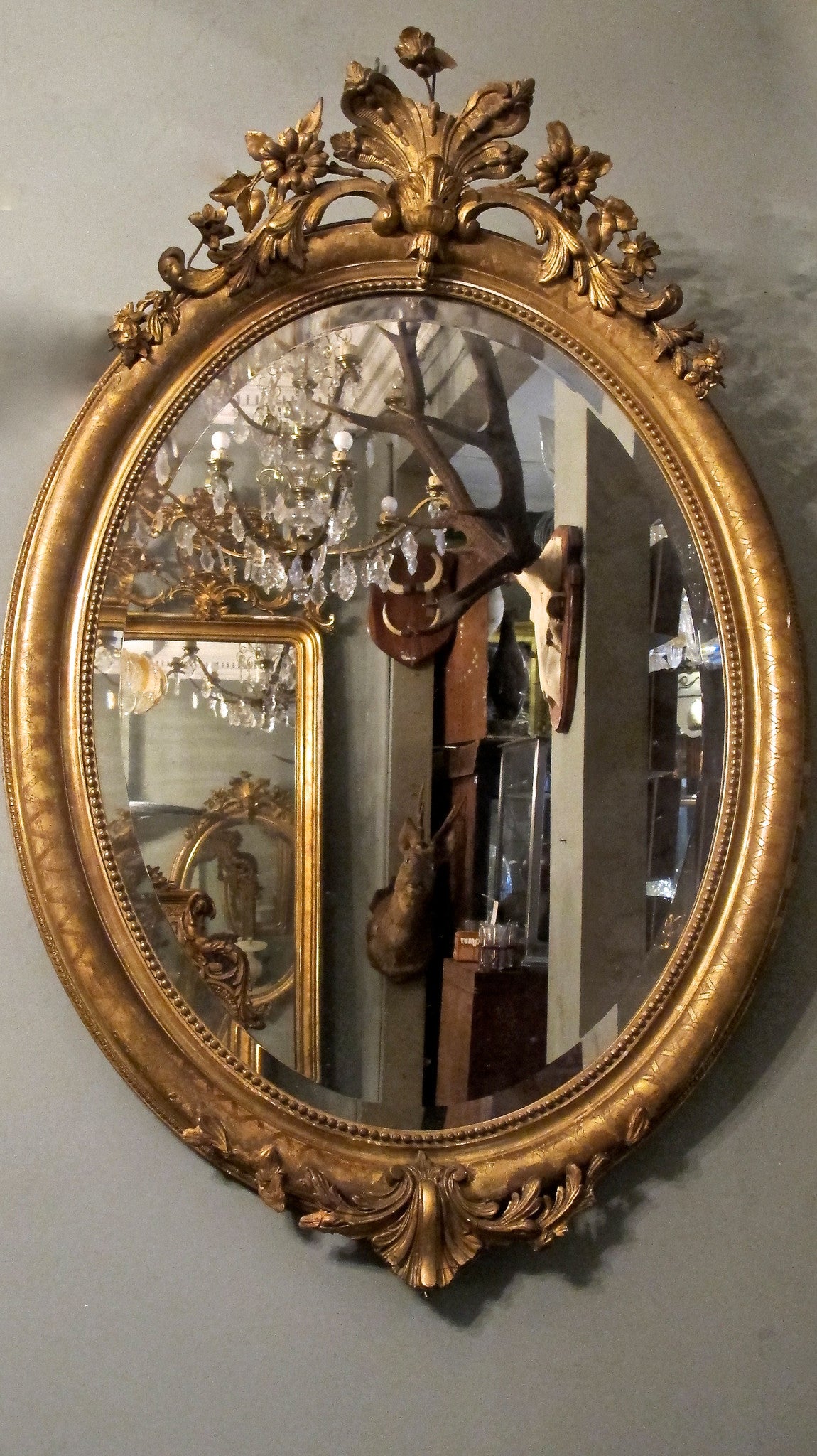 X A pretty gilt oval french mirror  with decorative crest.