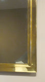 A large 1970s brass mirror with stepped edge detail.