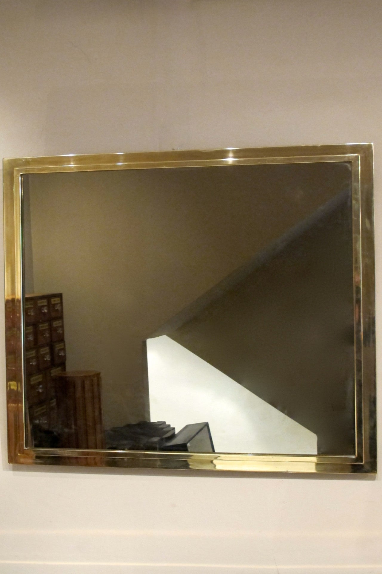 A large 1970s brass mirror with stepped edge detail.