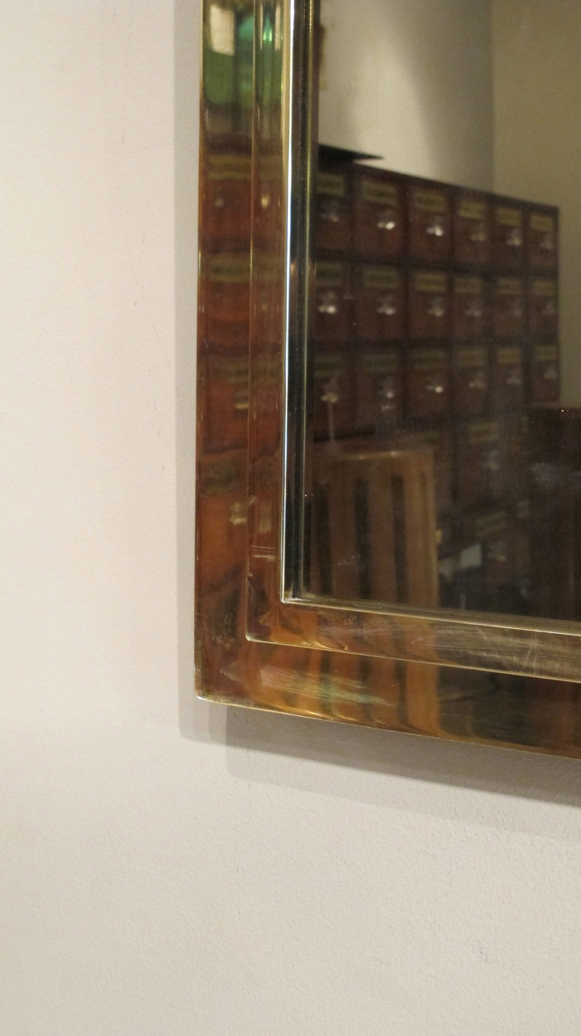A large 1970s brass mirror with stepped edge detail.